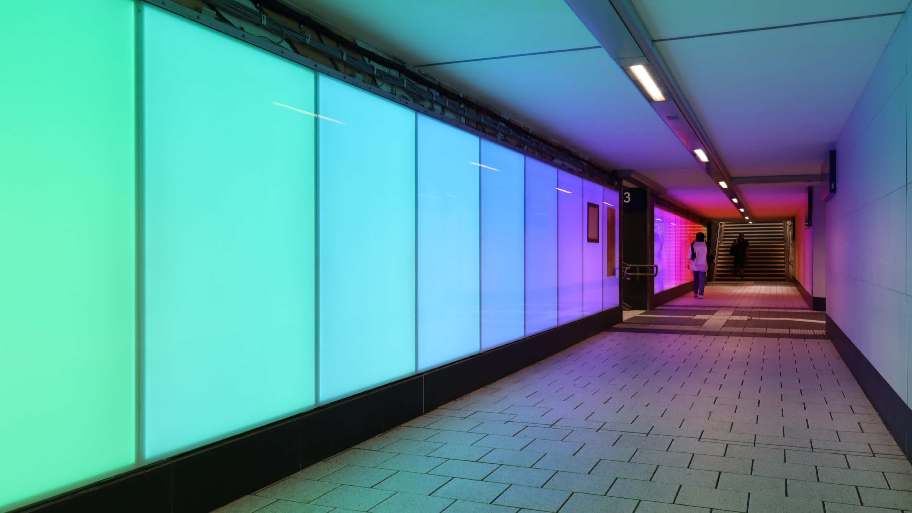 Bahnunterführung am Hauptbahnhof Miltenberg mit großen LED-Panels, die in allen Farben des Regenbogens leuchten.